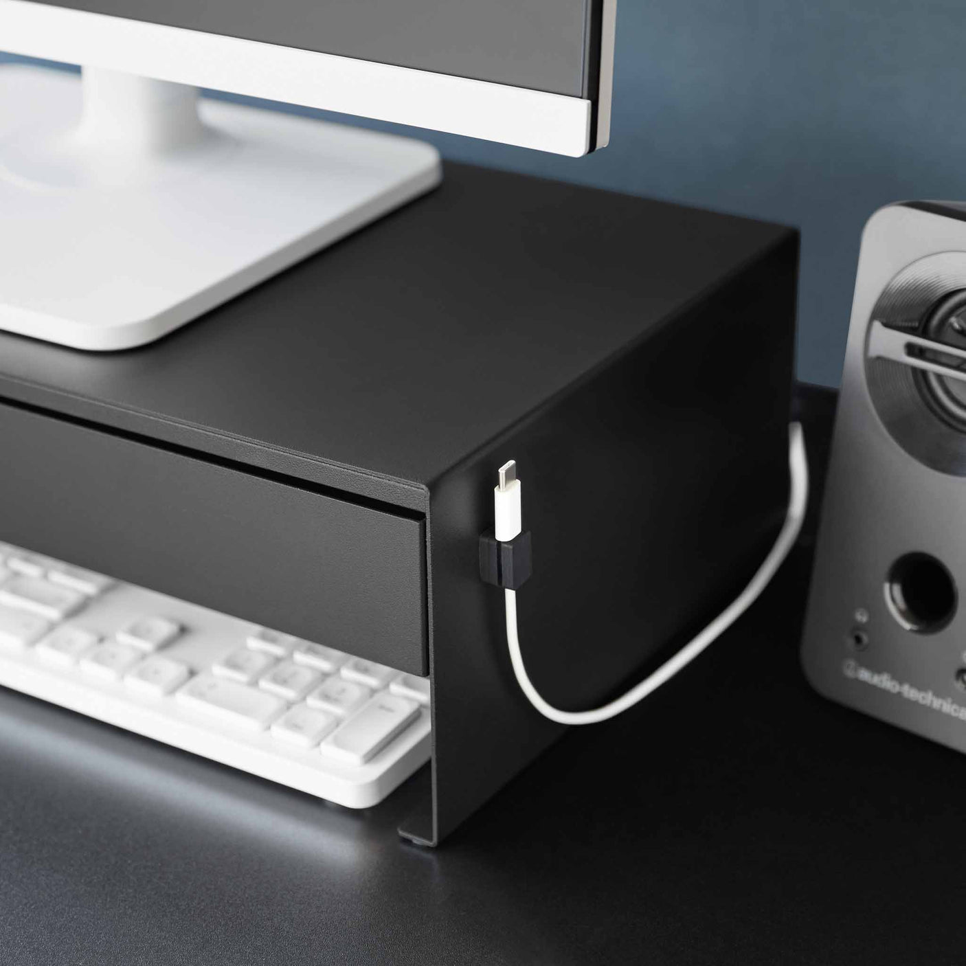 Sort skrivebordsorganisator som løfter skjermen og skjuler småting