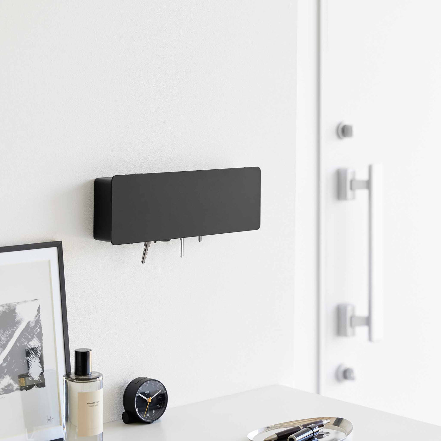 Veggmontert nøkkelskap i sort metall med diskré design