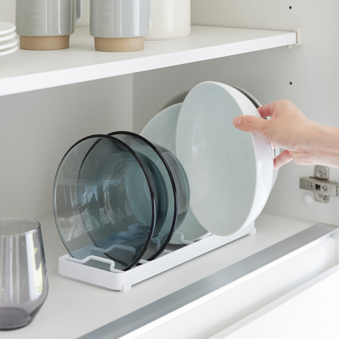 Skålstativ i hvit plast med silikonføtter, brukt til stablet kjøkkenutstyr.