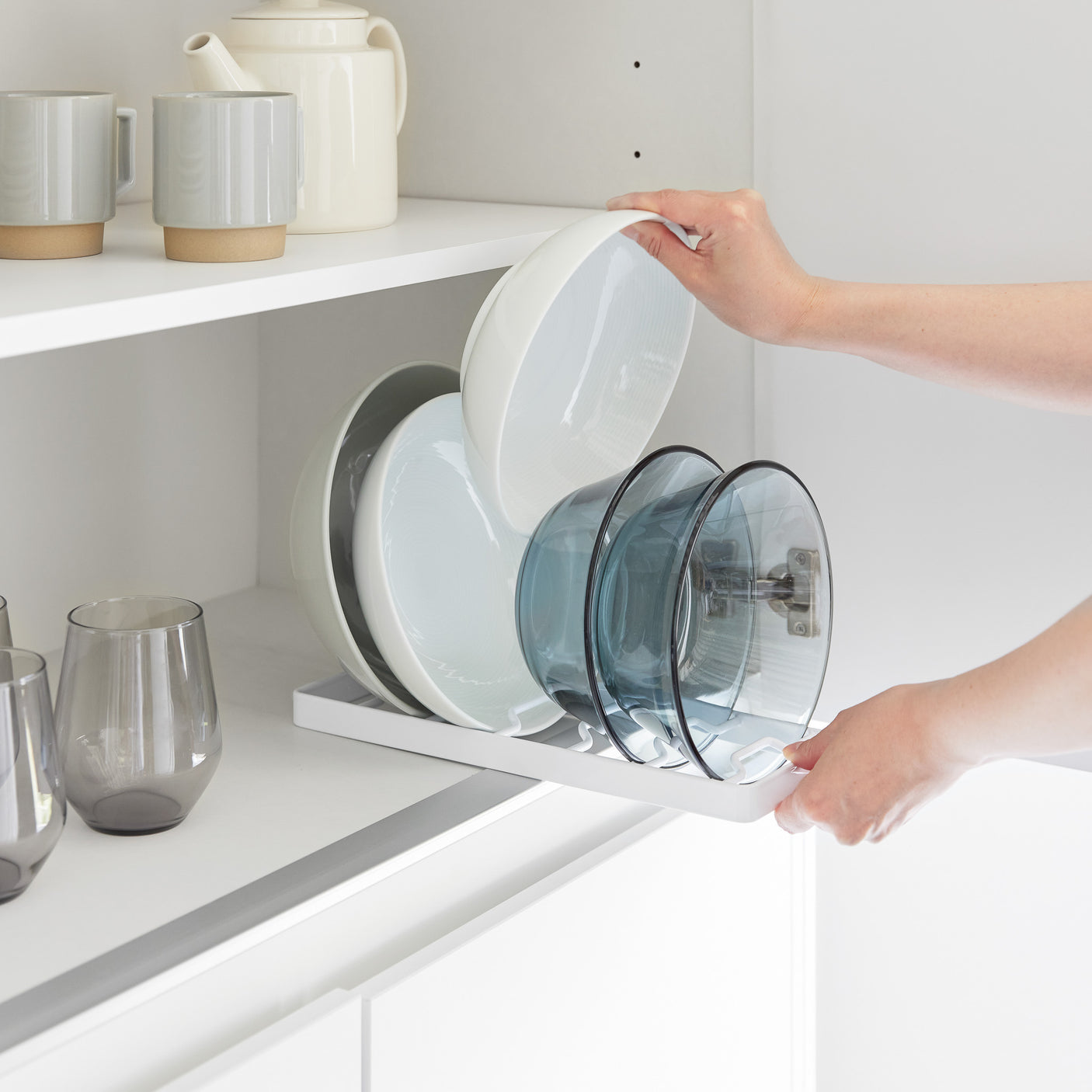 Hvit kjøkkenholder med plass til flere skåler, stående på benk ved siden av servise.