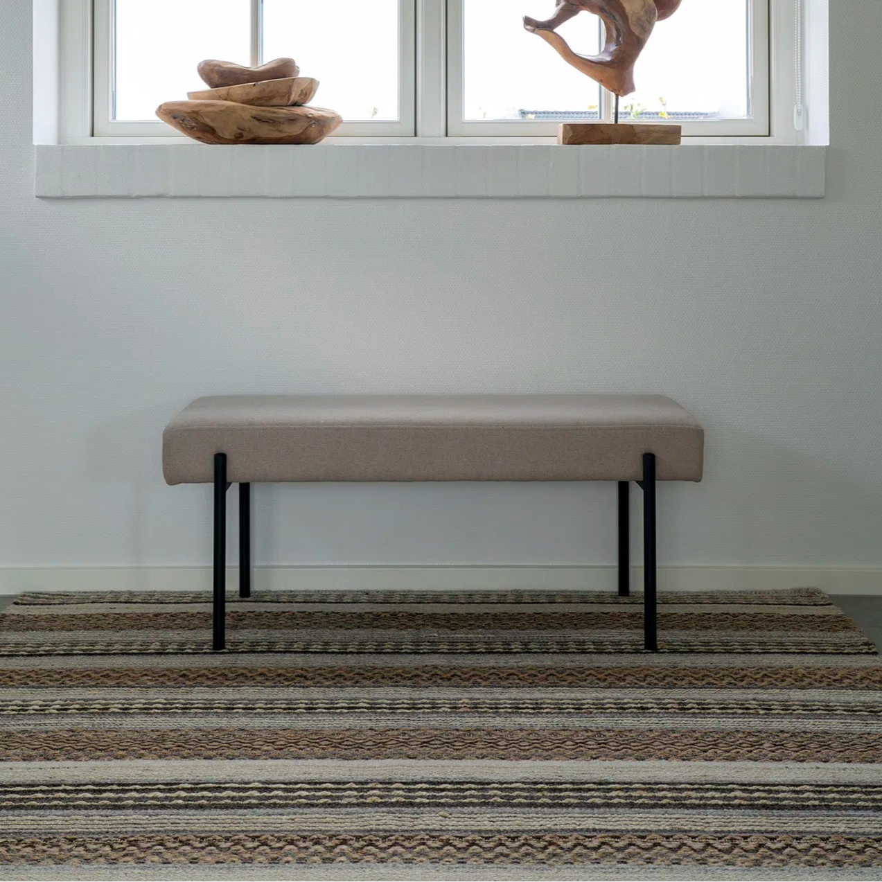 Steingrå benk med sorte metallben fra House Nordic, sett forfra mot hvit bakgrunn.