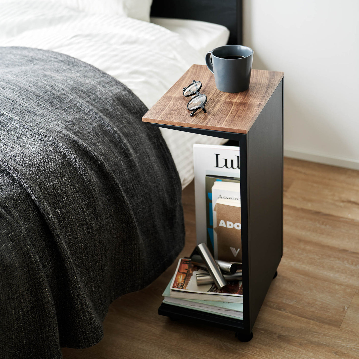 Sort metallbord med treplate, kompakt størrelse og hjul for enkel flytting.