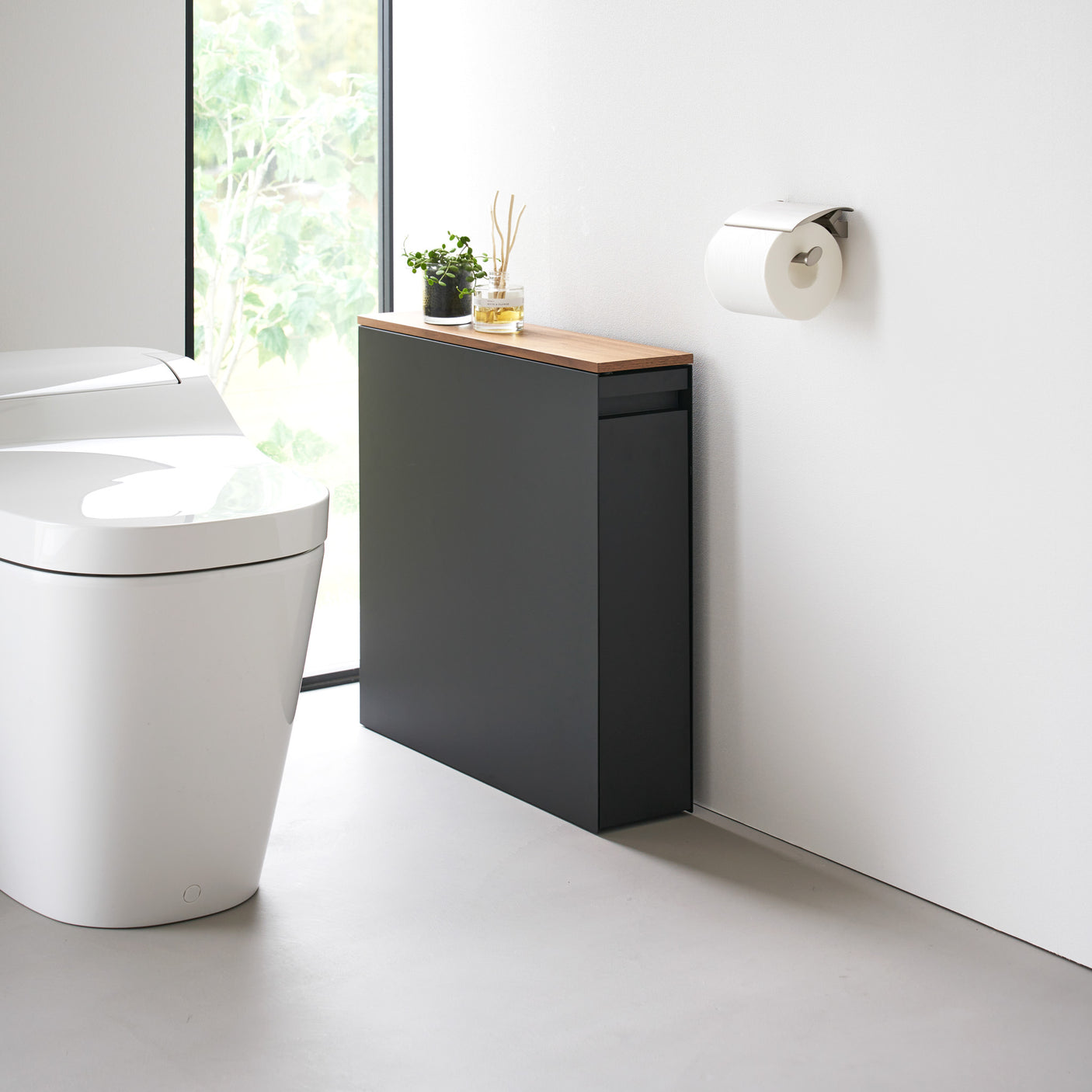 Sort oppbevaringsmøbel med lys treplate i moderne baderom.