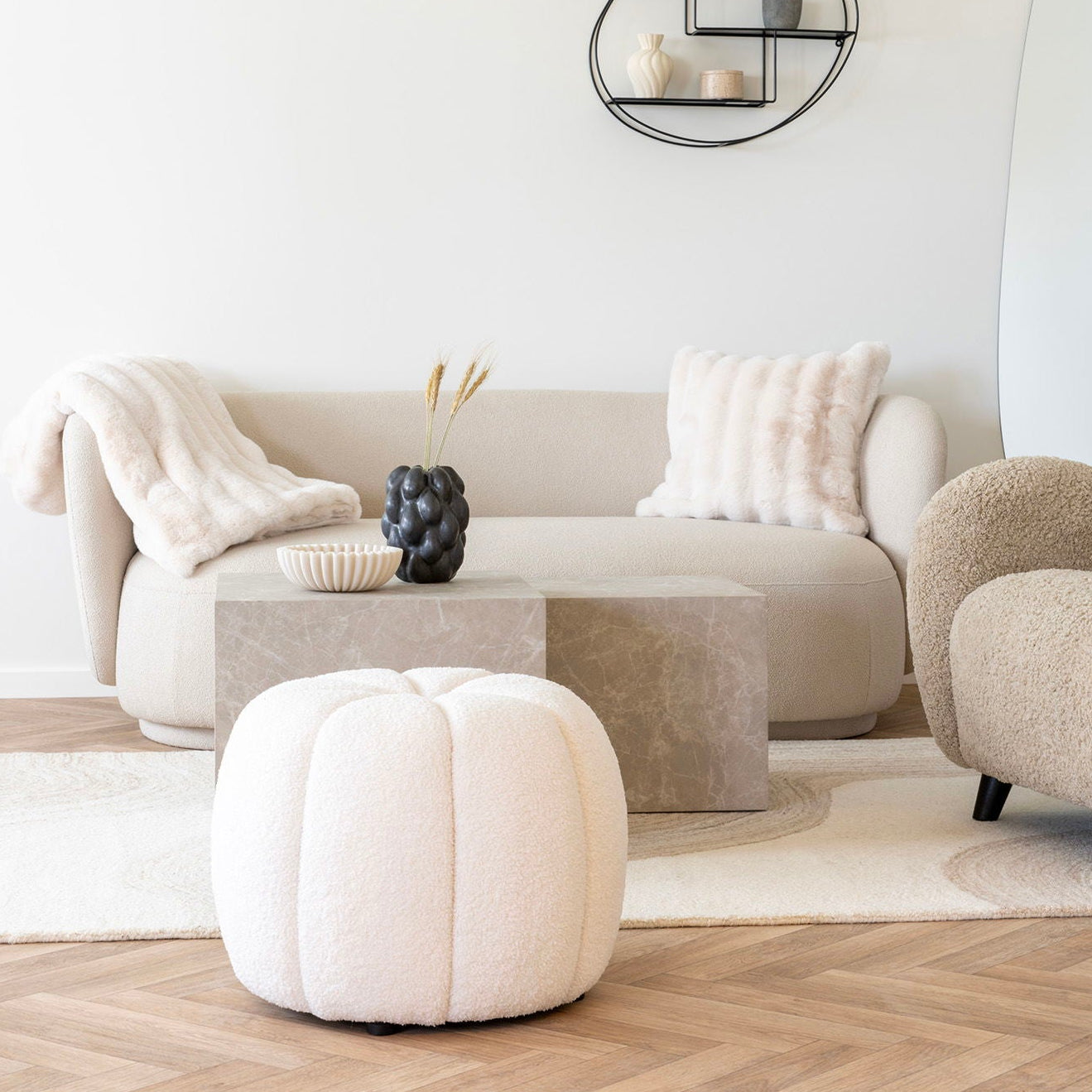 Offwhite teddy puff plassert ved sofa i lyst interiør