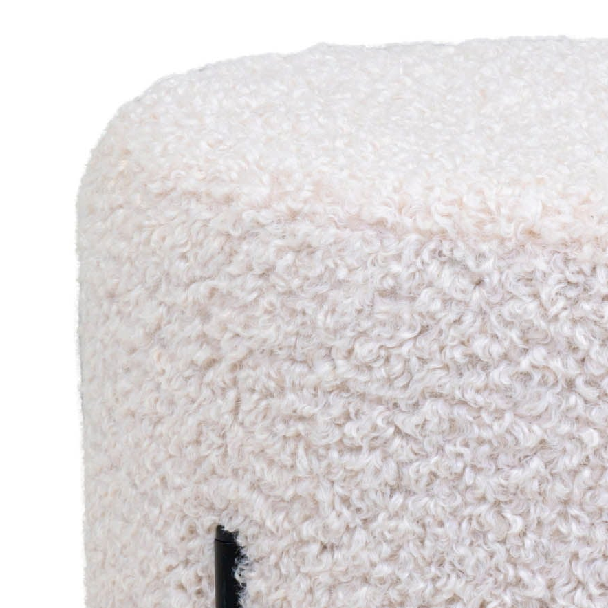 Rund puff med myk teddytekstur i lys farge og sorte ben