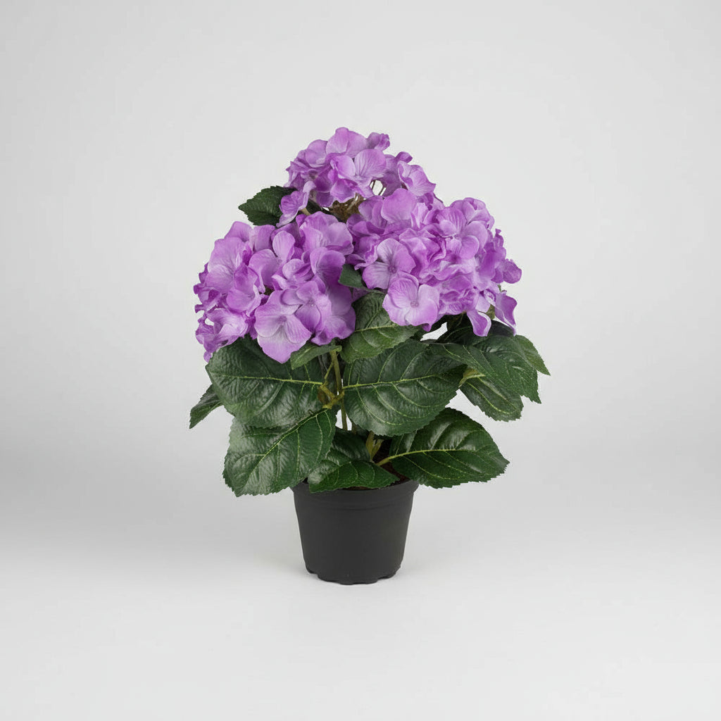 Naturtro kunstig hortensia med lilla blomster og grønne blader i sort potte.