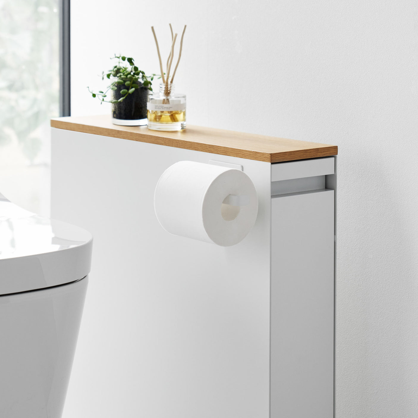 Hvit magnetisk dorullholder festet på siden av et baderomsskap.