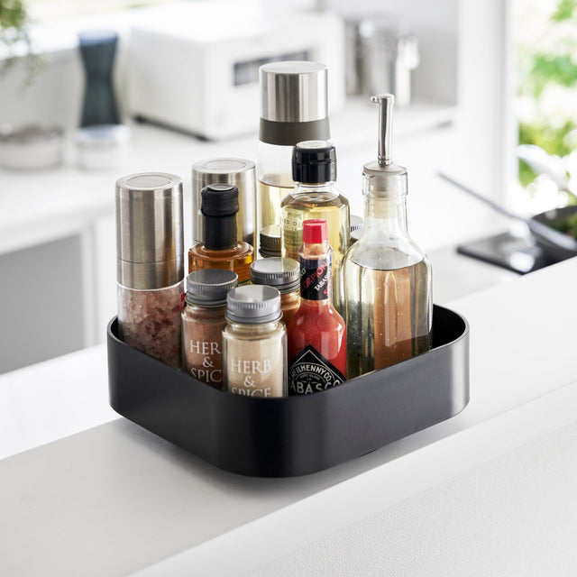 Roterende oppbevaringsbrett i sort for organisering av kjøkkenartikler.