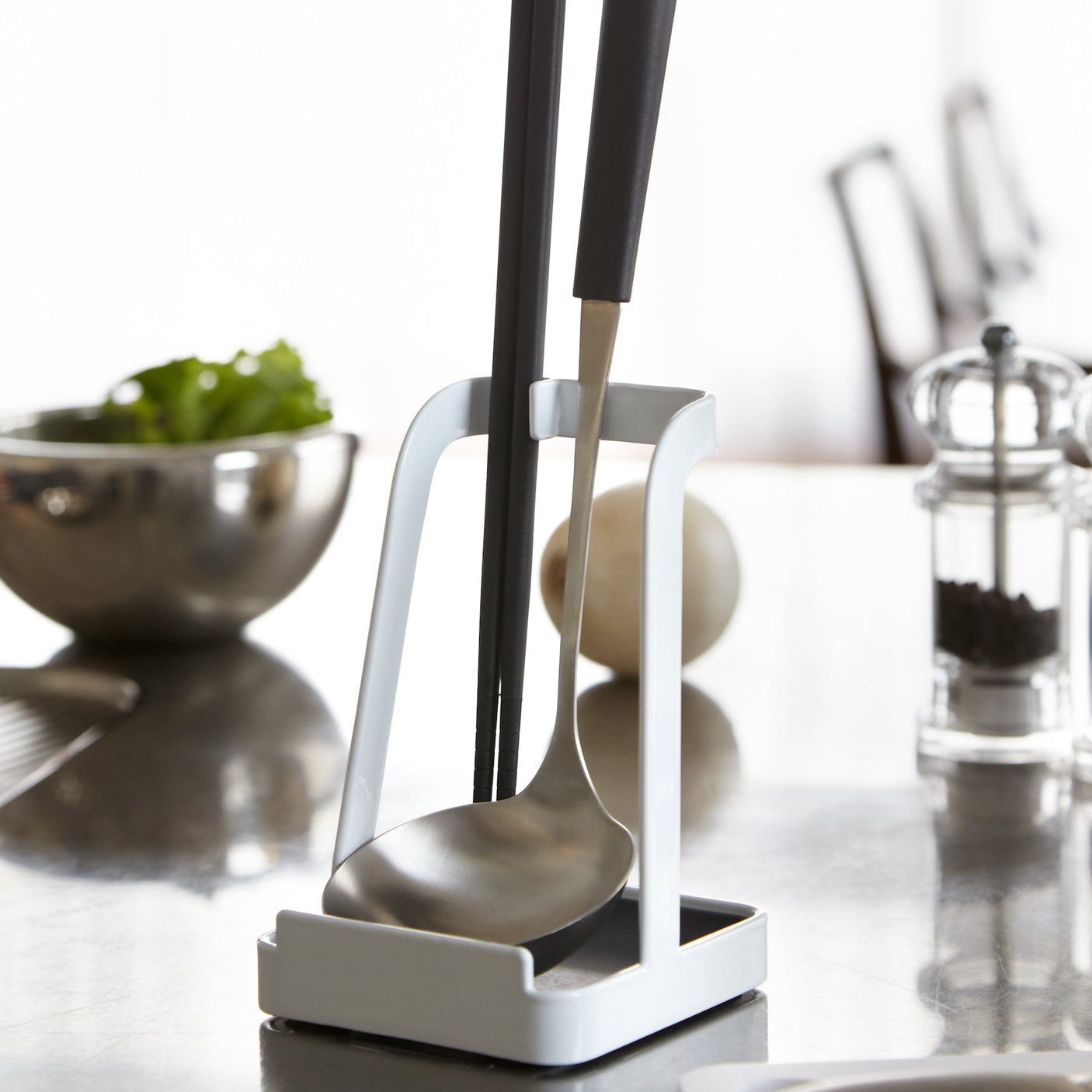 Hvit kjøkkenredskap stativ for oppbevaring av sleiver og lokk.