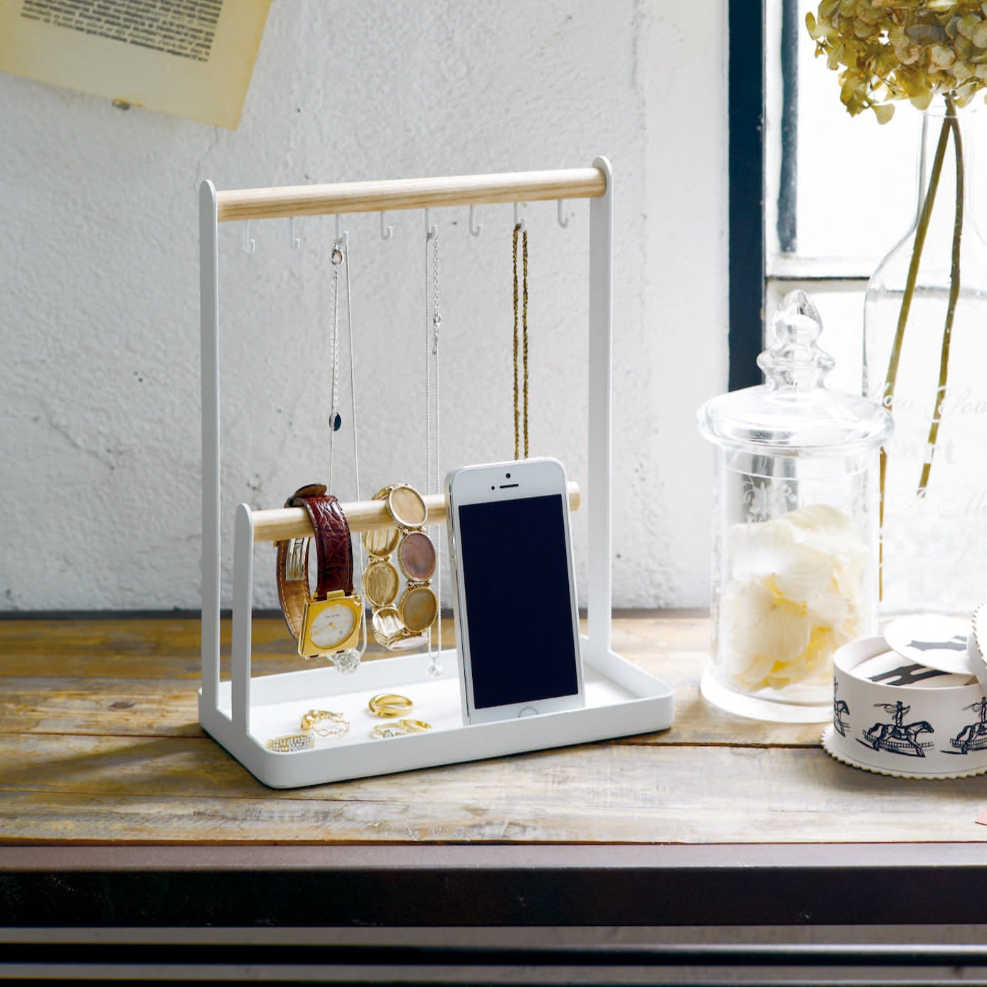 Smykkestativ med kjeder, armbånd og klokker organisert på ulike deler av stativet.