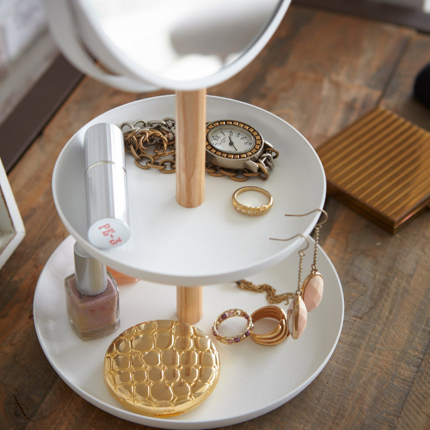 Nærbilde av smykkebrettets to oppbevaringsnivåer med ulike småting