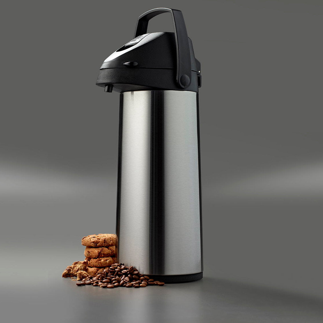 Pumpekanne i matt stål i stemningsbilde med kaffebønner og kjeks