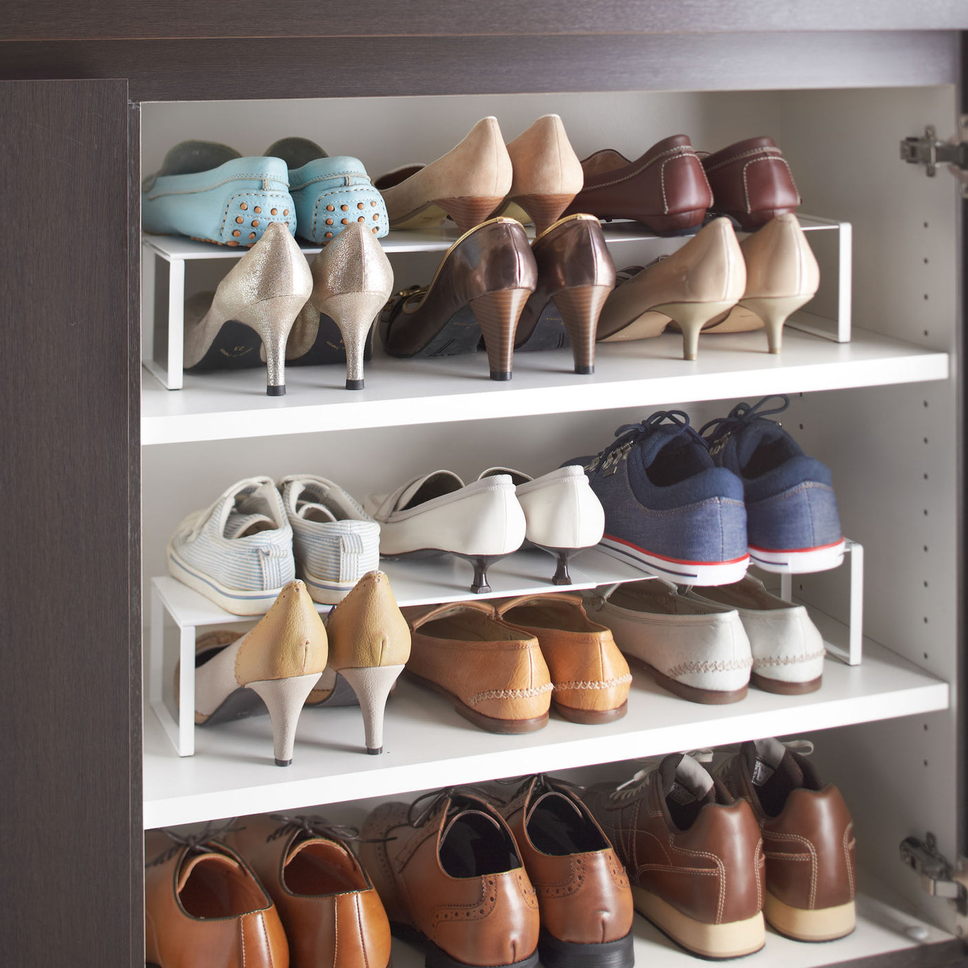 Flere hvite stålhyller stablet med sko i gang