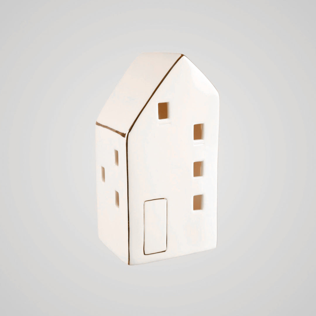 Hvitt keramikkhus med flere små vinduer, fotografert mot lys bakgrunn.