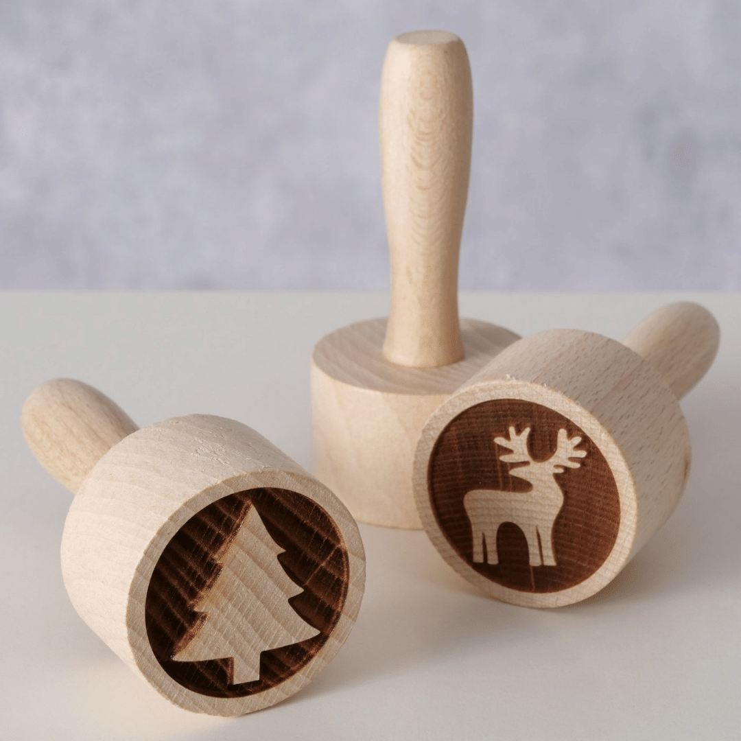 Tre kakestempler i tre med reinsdyr- og juletremotiv på lys bordflate.