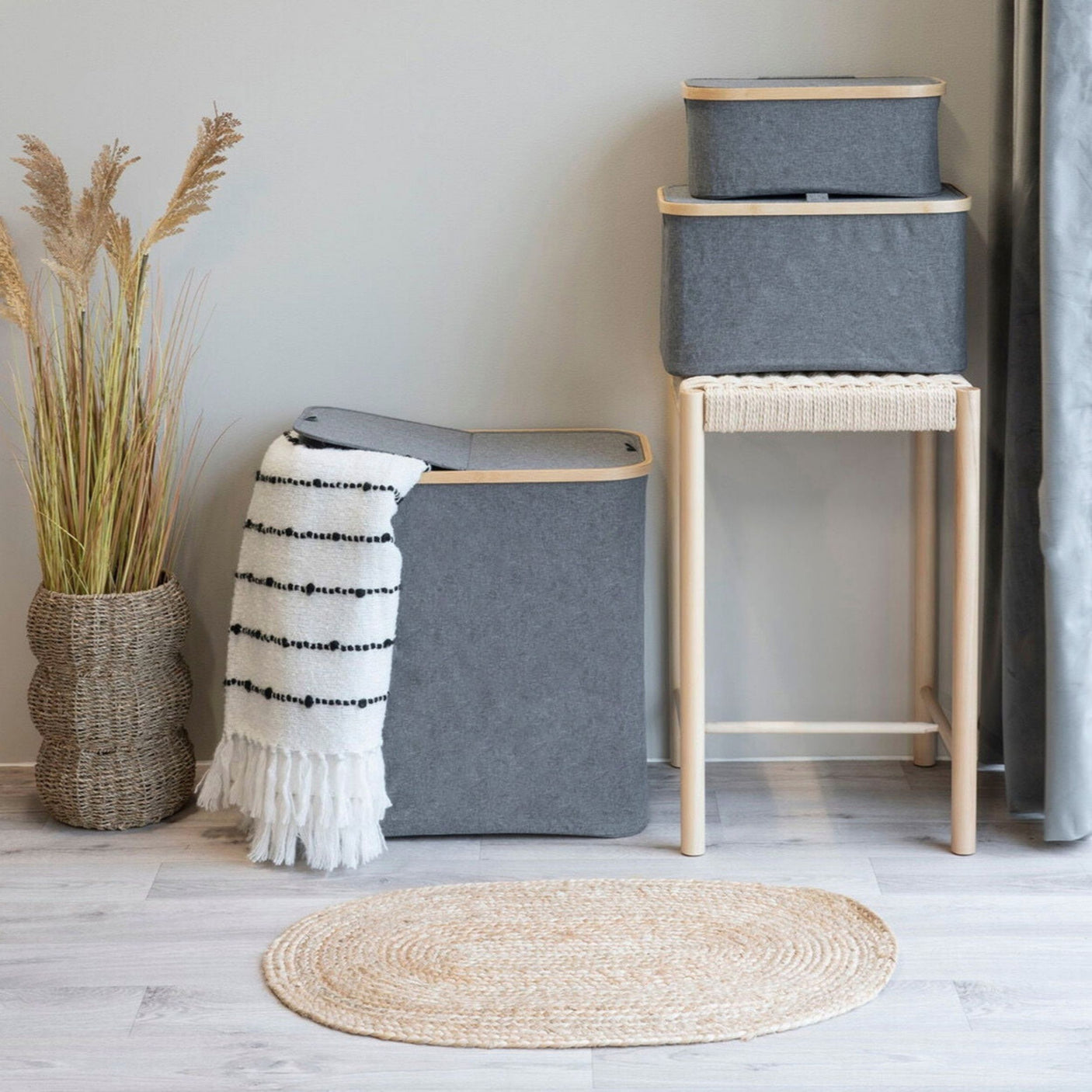 Stilren skittentøyskurv i grått stoff og bambus brukt i vaskerom med kurver og dekor.