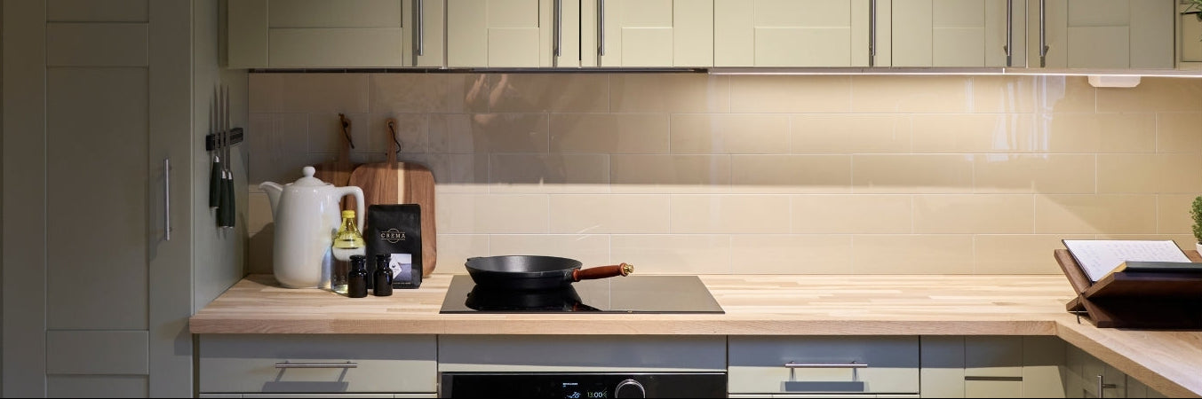 Detalj av kjøkkenet i Sykepleierhytten etter oppussing i Eventyrlig Oppussing, med grønne skapfronter, beige Hailey-fliser og lyse trematerialer fra Lindas Dekor.