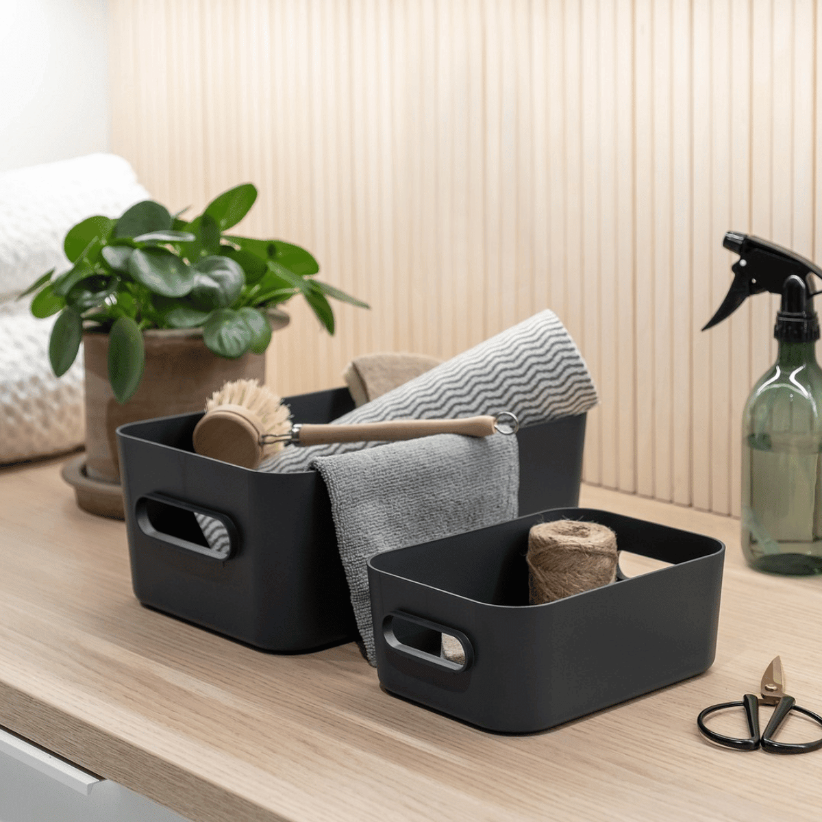 To koksgrå SmartStore Comfort oppbevaringskurver med oppvaskbørste, klut og rengjøringsutstyr på benk