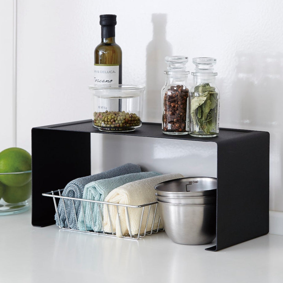Sort stablehylle for organisering av kjøkkenutstyr og krydder.