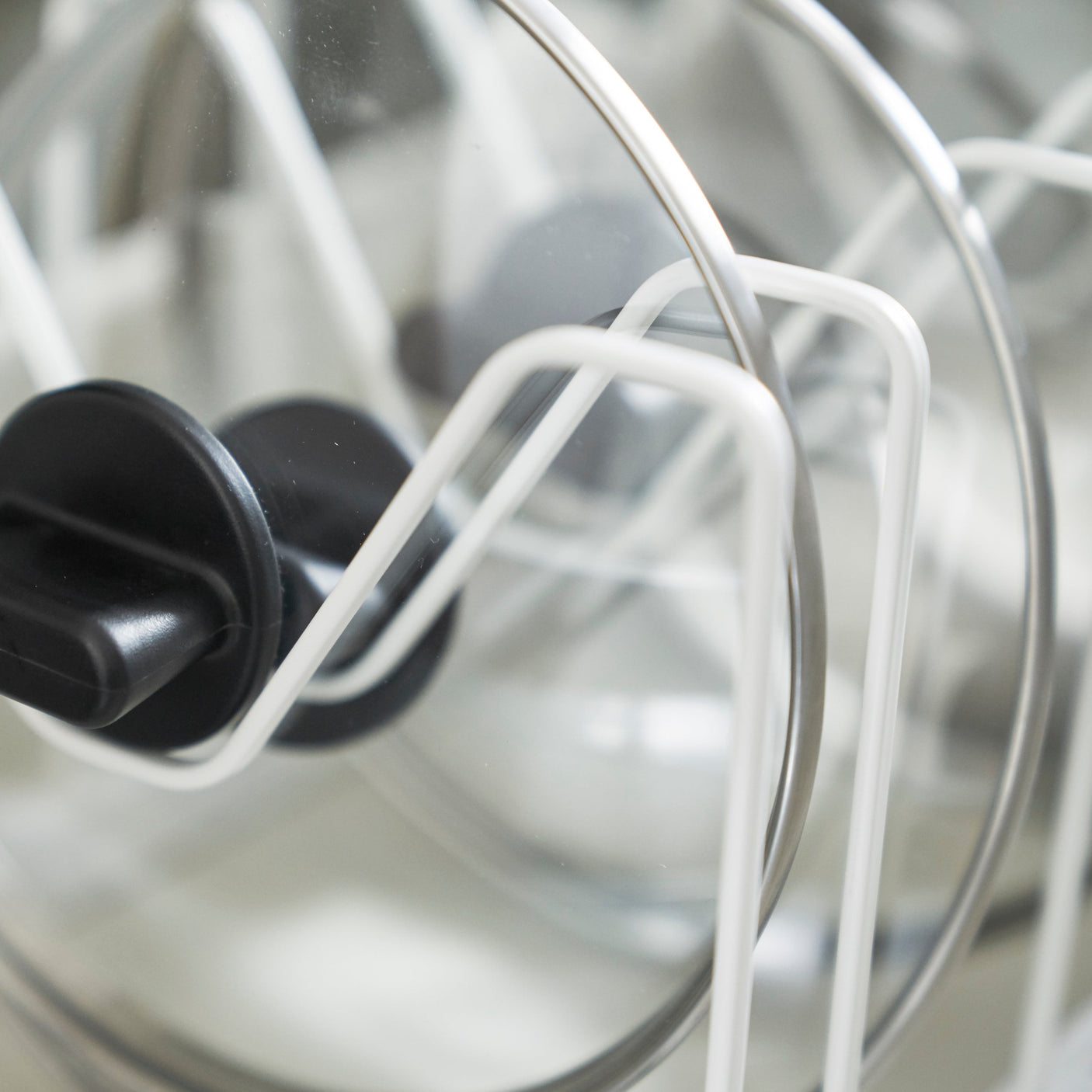 Kjøkkenorganisering med hvitt metallstativ for gryter og lokk.