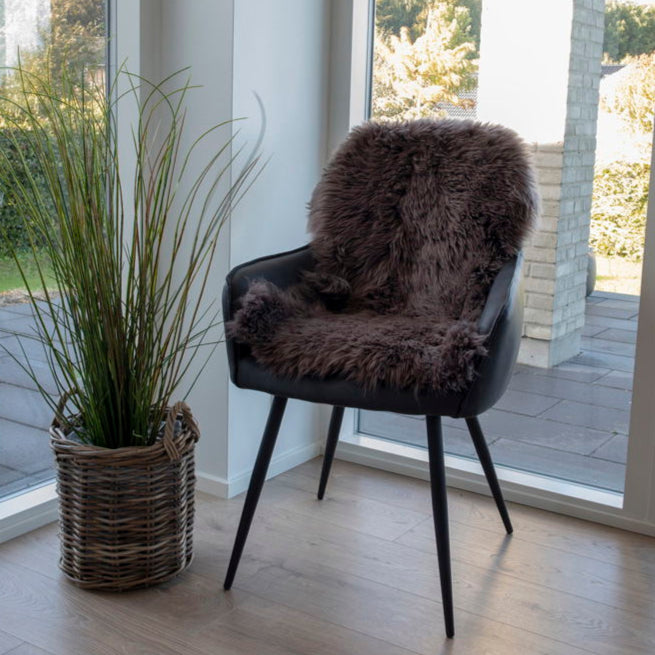 House Nordic lammeskinn i varm brunfarge brukt som gulvteppe ved peisen.