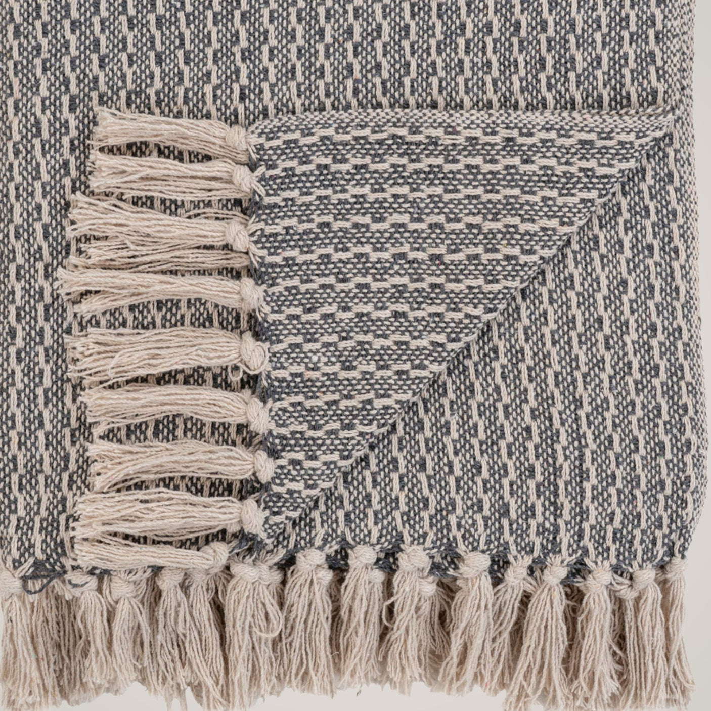 Kvadratisk bilde av Cort pledd brettet på sofa i lyse omgivelser