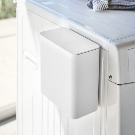 Hvit magnetisk oppbevaringsboks festet på vaskemaskin.