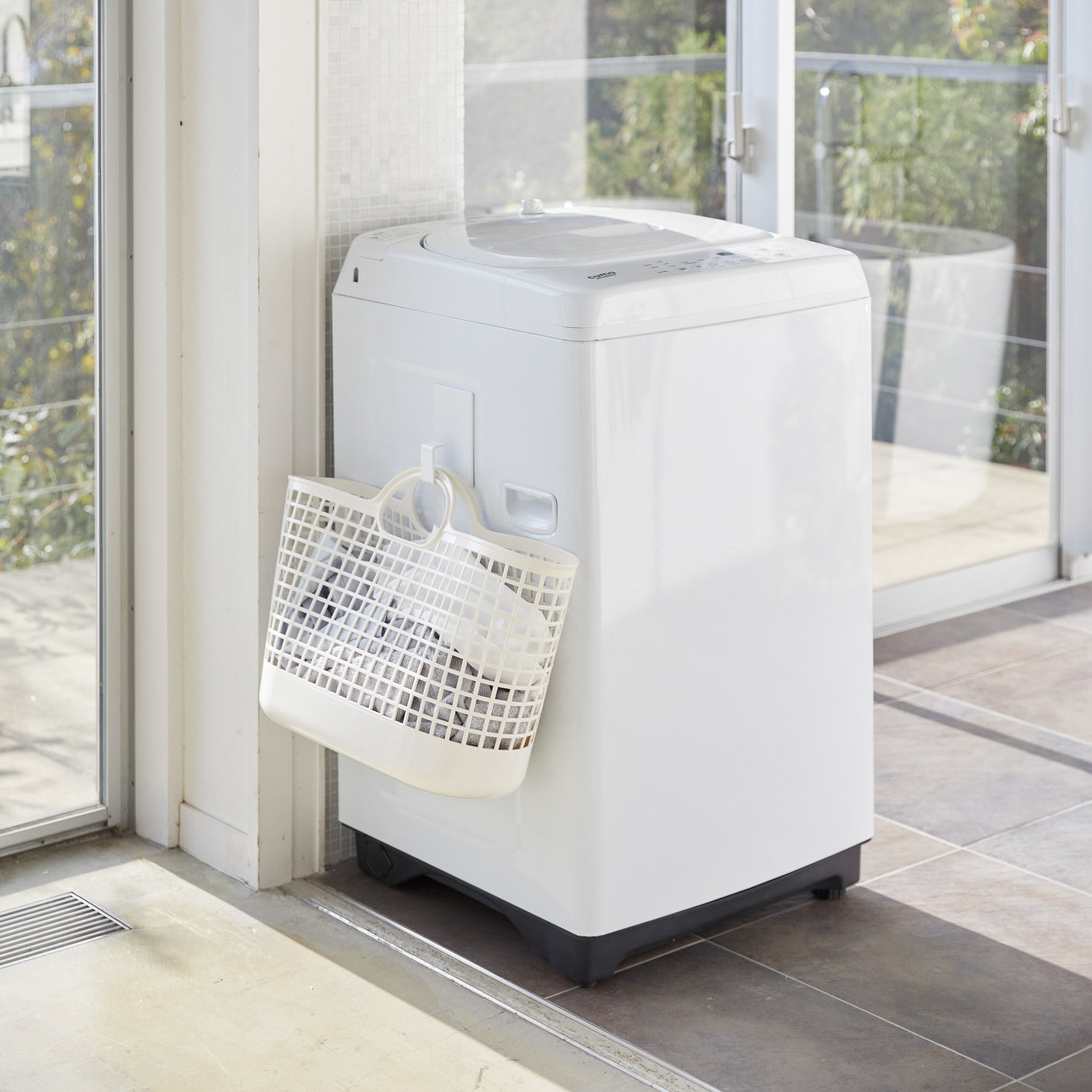 Hvit krok med magnetfeste holder skittentøyskurv på plass.