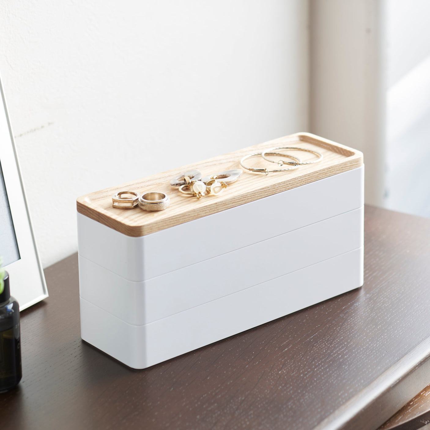 Hvit oppbevaringsboks med trelokk for smykker og småting.