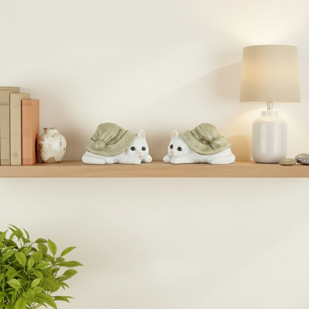 To små kattefigurer i polyresin med grønne luer på hvit bakgrunn