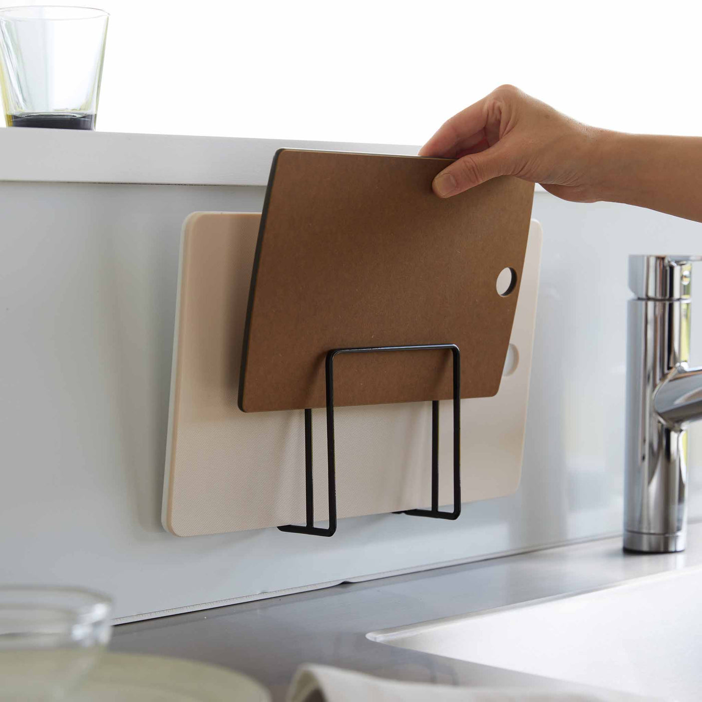 Sort selvklebende holder til skjærebrett med to rom montert på kjøkkenvegg