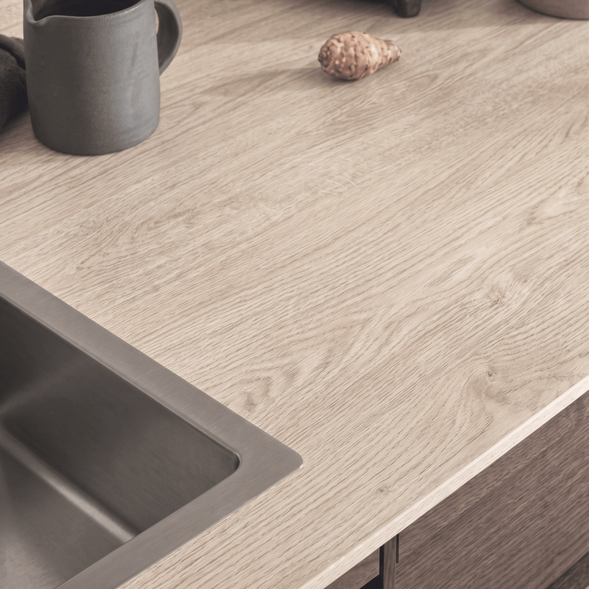 Nærbilde av kjøkkenbenk med Blond Oak kontaktplast rundt vasken, lys eikestruktur med årer