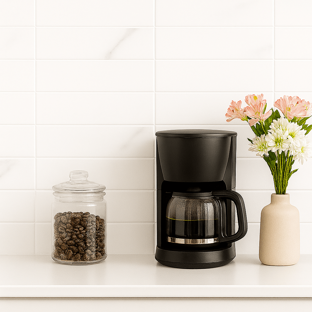 Kaffestasjon med hvit marmorlook-flis, kaffetrakter, glasskrukke med kaffebønner og blomster i beige vase på lys kjøkkenbenk.