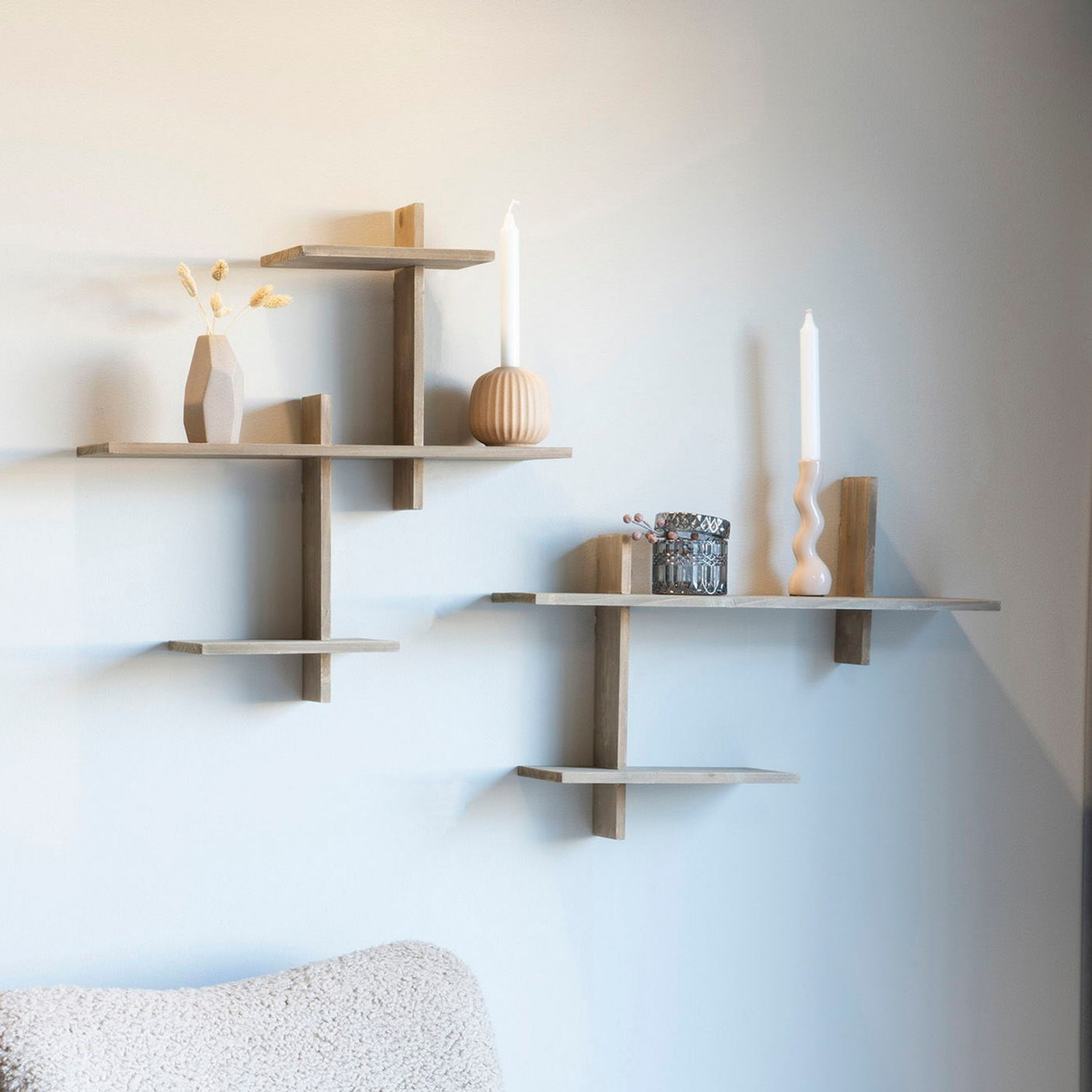 Gavi hylle i naturfarget furu montert på lys vegg i stue, dekorert med bøker og keramikk – moderne, nordisk interiør.