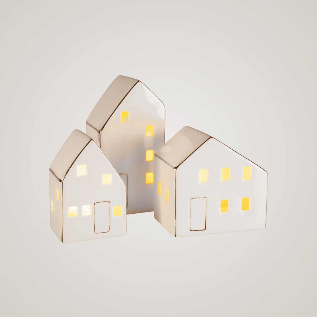 Tre små keramikkhus lyser varmt fra innsiden – perfekte som stemningsfull bord- eller vindusdekor.