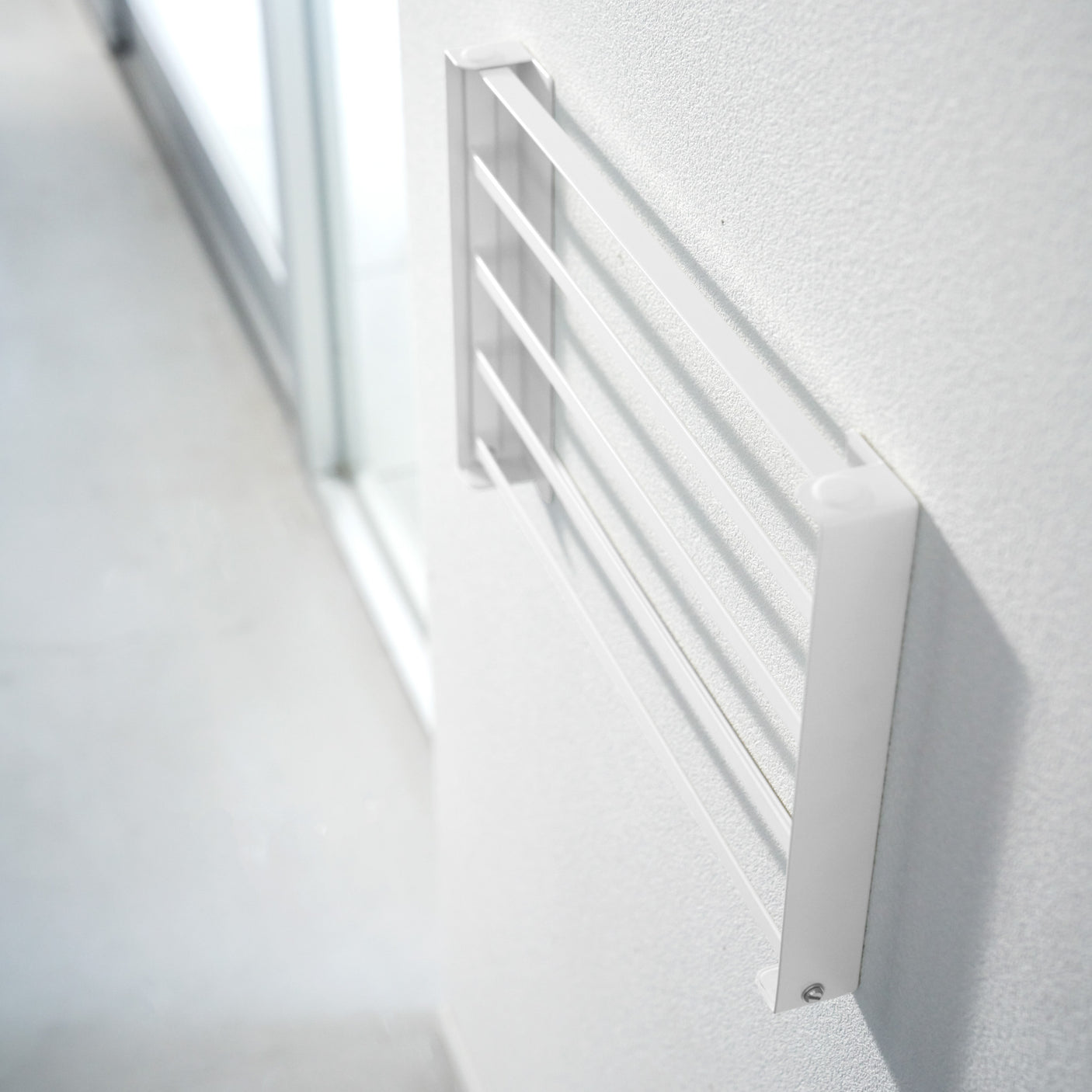 Hvit sammenleggbar hylle brukt til oppbevaring av håndklær på bad.