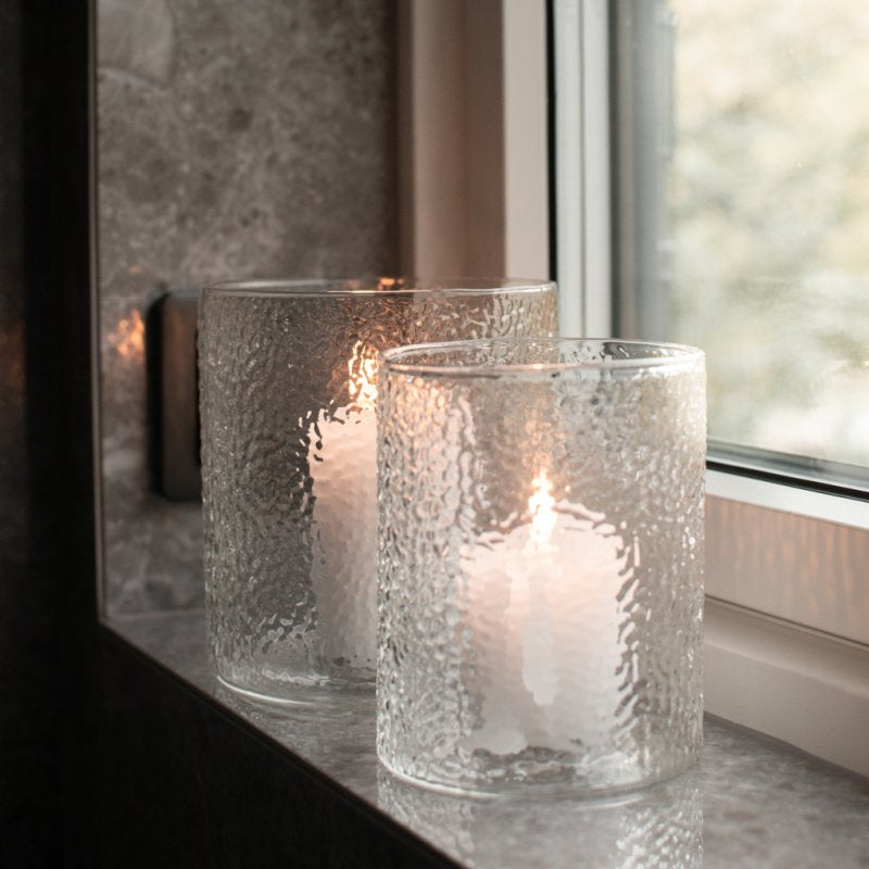 To store glasslykter med kubbelys på en vinduskarm i naturstein.