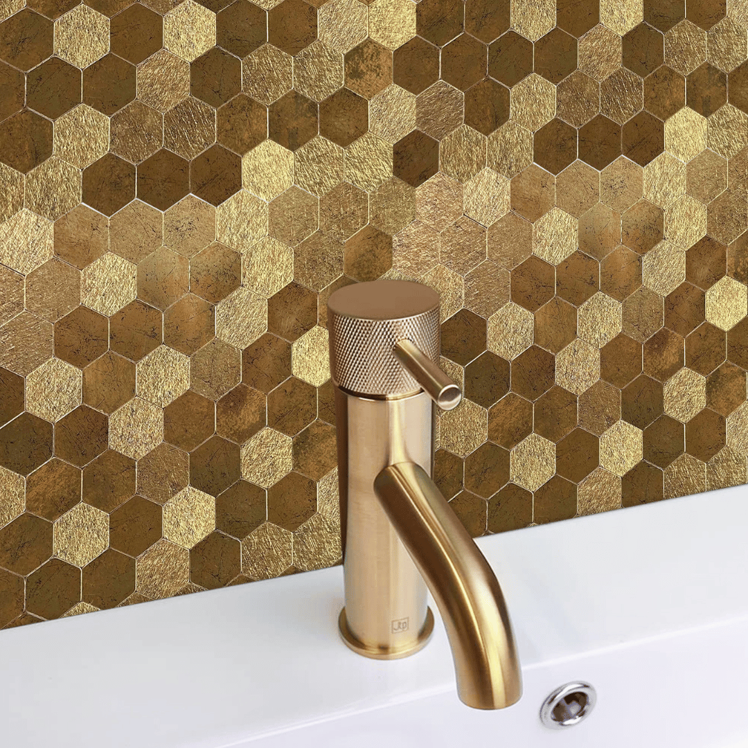Selvklebende veggfliser i gyllen hexagonform montert bak en gullfarget servantkran.