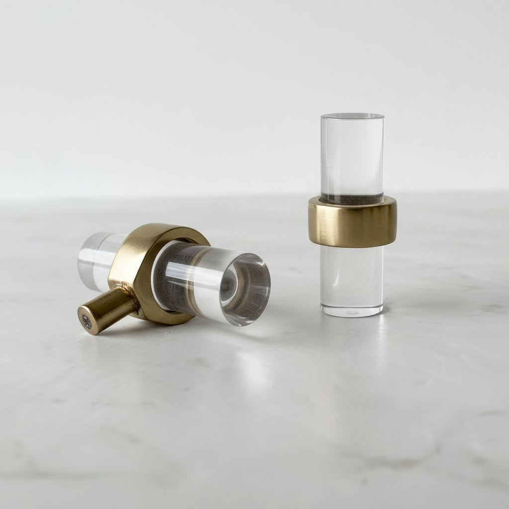 To Nesu T-bar knotter i glass og messing liggende på lys overflate.