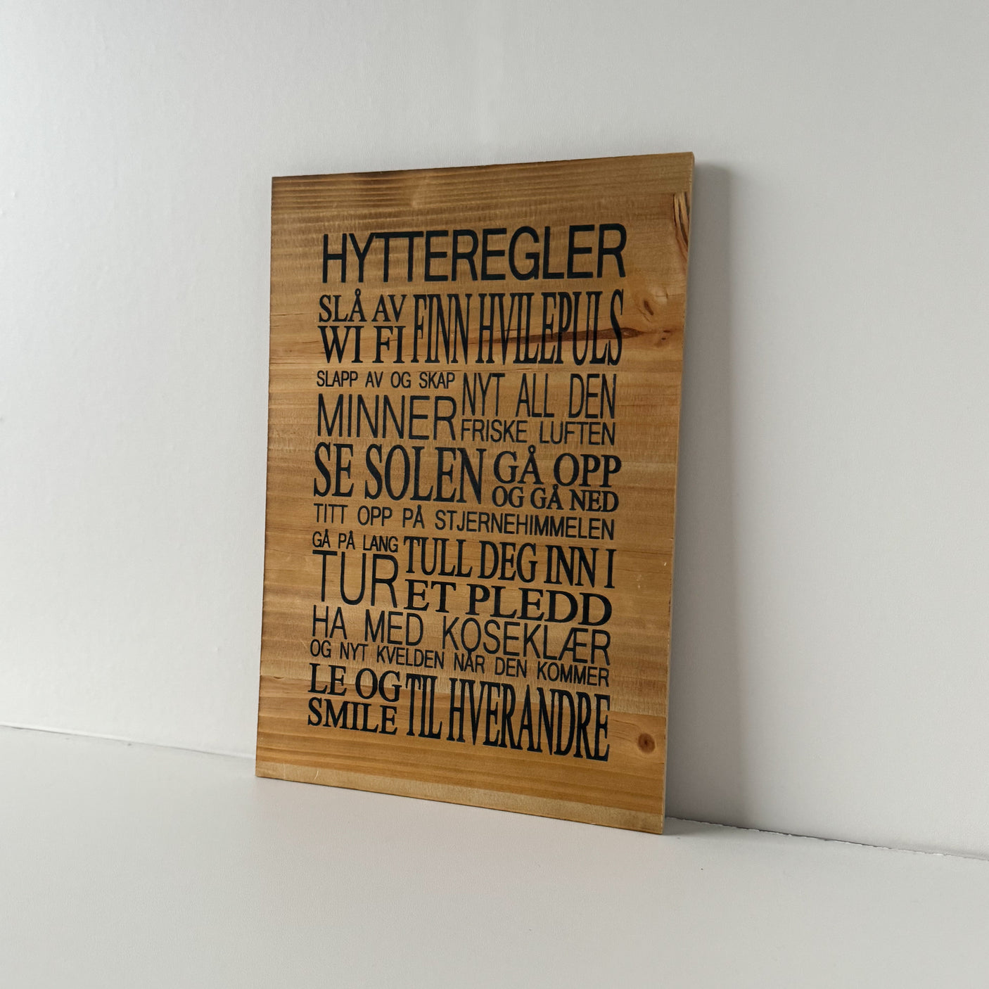 Skilt med hytteregler i naturbrune farger til veggdekor på hytta.