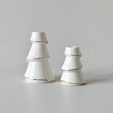 To hvite lysestaker formet som juletrær i ulik størrelse med gullkant.