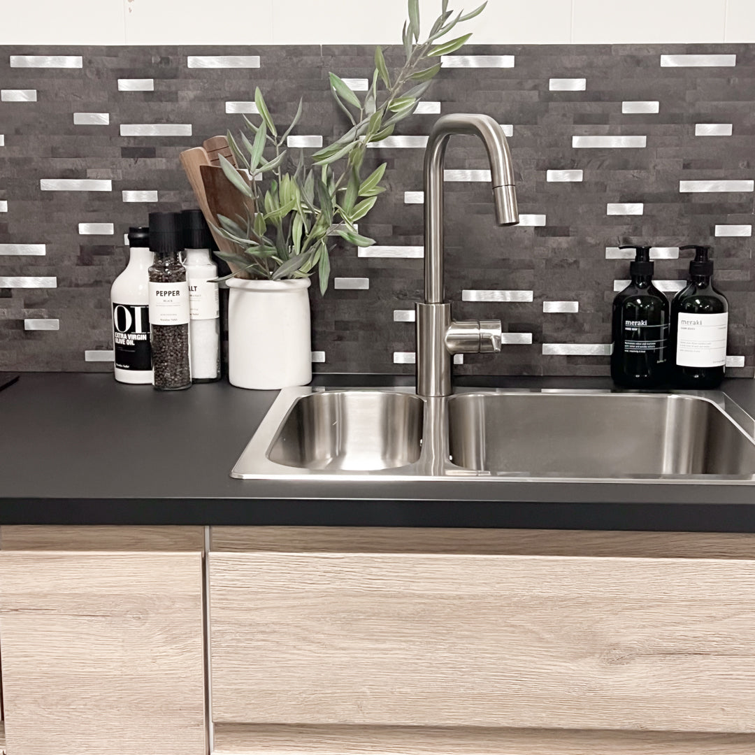 Mørk grå selvklebende veggfliser med steinmønster og detaljer i børstet aluminium.