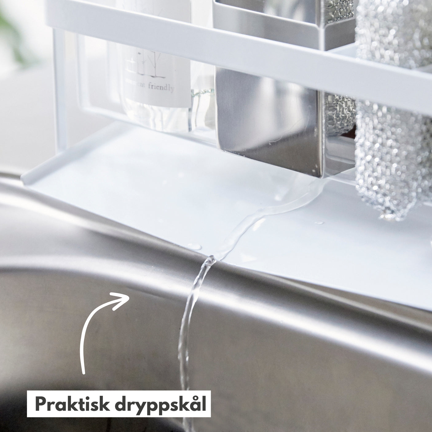 Nærbilde av hvit såpeholder i bruk ved kjøkkenvask.