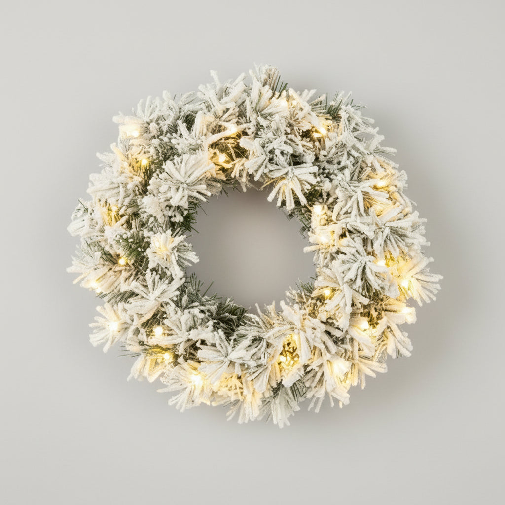 Julekrans med snø og varme LED-lys, sett forfra mot hvit bakgrunn.