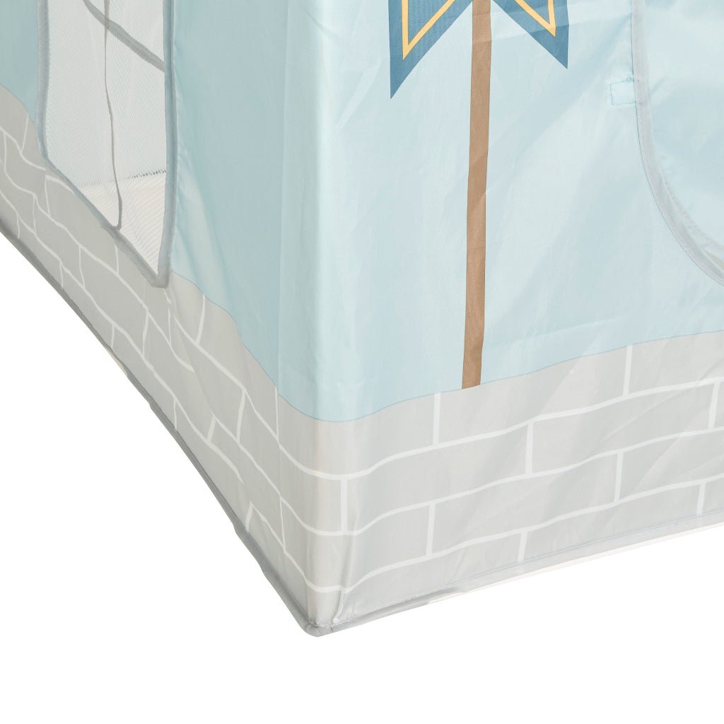 Nærbilde av blått slottsformet leketelt med dekorativt flagg og grå murdetaljer nederst.