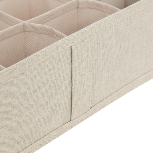 Nærbilde av beige skuffeorganiser med stofftrukne skillevegger og rominndeling.