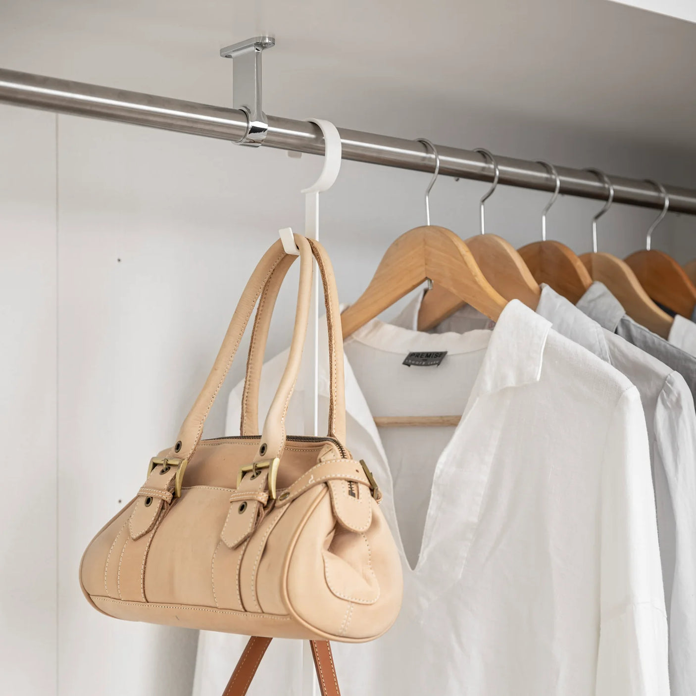 Oppbevaringsløsning til garderobe med to stenger og kroker i hvitt metall nærbilde