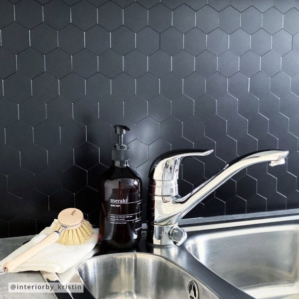 Sorte sekskantede selvklebende fliser på kjøkkenvegg, moderne og stilren backsplash bak vasken.