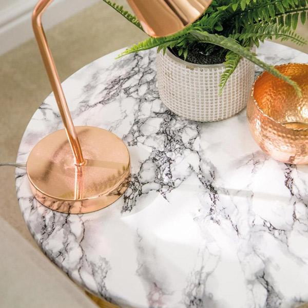 Marmor hvit med sorte årer kontaktplast – dekorfolie brukt på rundt bord, gir en luksuriøs marmorlook i kombinasjon med kobberdetaljer og grønn plante.