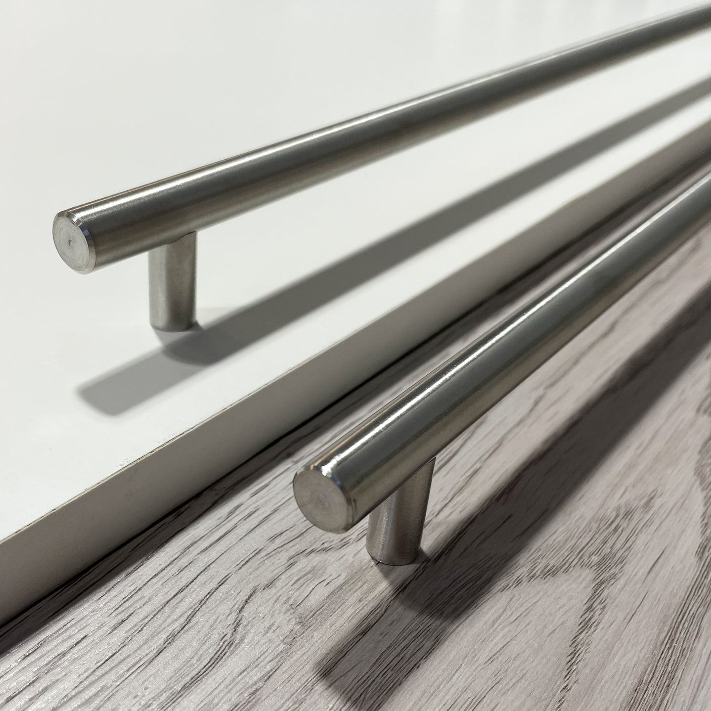 Moderne håndtak i rustfritt stål montert på mørk skuffefront.